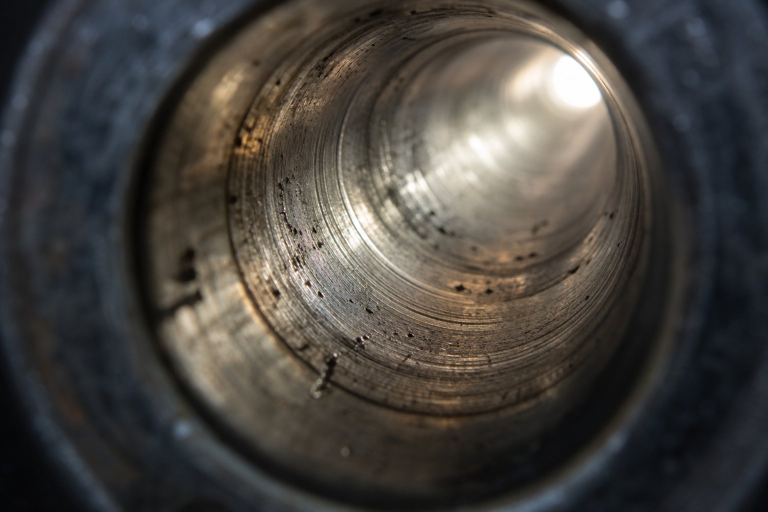 interior view of a worn injection molding barrel bore showing scoring and pitting from combined abrasive and corrosive wear