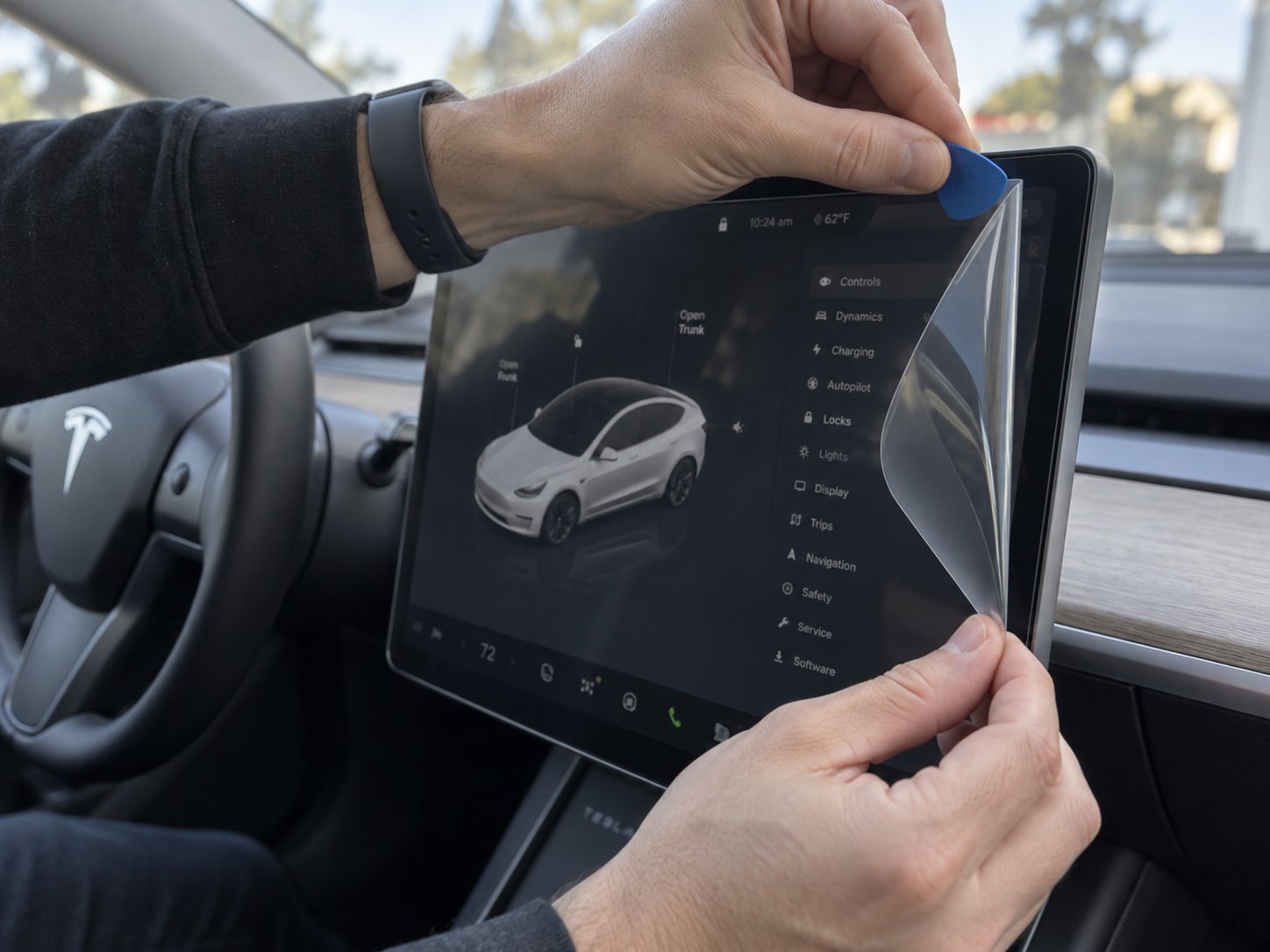 carefully lifting a tempered glass screen protector from a tesla touchscreen using a plastic pry tool