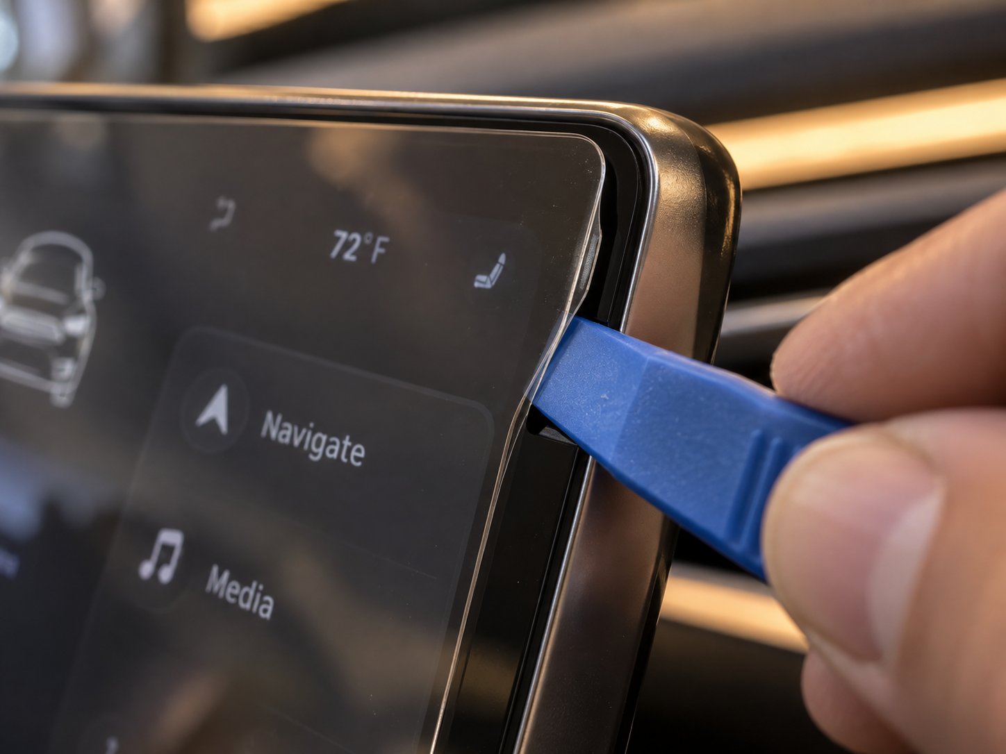 using a plastic pry tool to gently lift the corner edge of a tesla screen protector