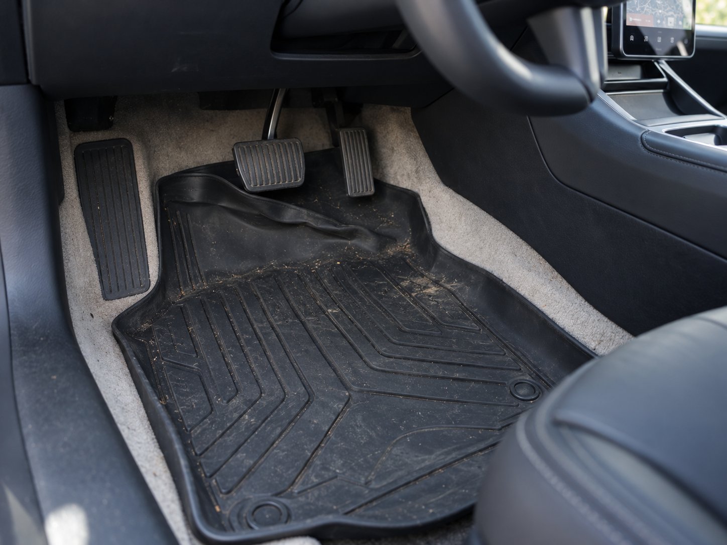a poorly fitted universal mat shifting toward the brake pedal in a tesla model 3 footwell